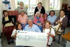 Lauren Tinkler and Hannah Swainston present a cheque to Maryport Cottage Hospital after a yard sale where popcorn, cakes and drinks were provided